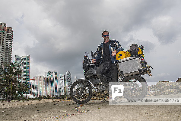 Man posing next to his adventure motorbike after a long trip  Columbia