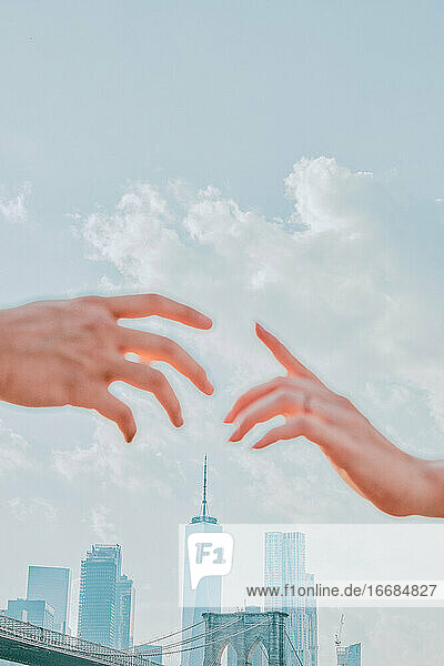 Zwei Hände  die sich kaum berühren  gegen die Skyline.