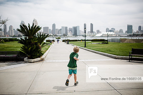 Junger Junge läuft mit San Diego Skyline im Hintergrund