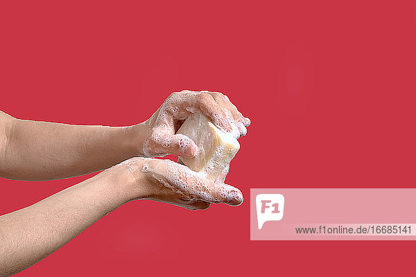 Frau wäscht Hände mit Seife auf einem roten Hintergrund
