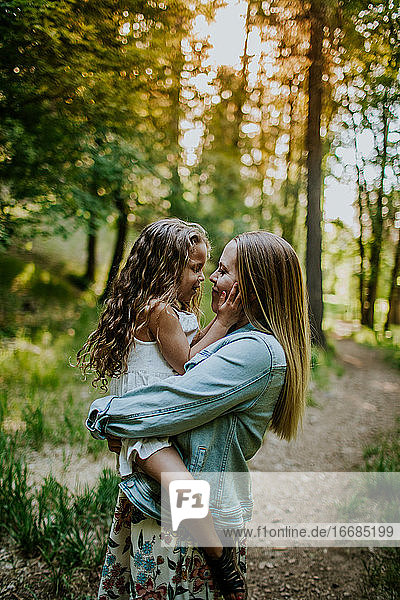 Glückliche Mutter hält junges Mädchen im Wald
