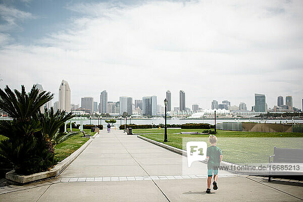 Junger Junge läuft mit San Diego Skyline im Hintergrund