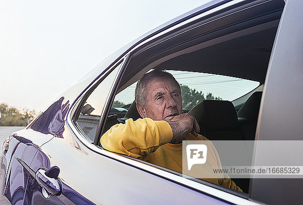 Ein alter Mann sitzt auf dem Rücksitz eines Elektroautos