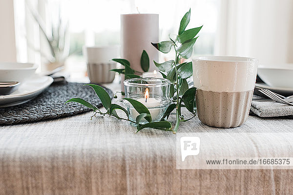Kerze und Pflanzen auf einem Esstisch für zwei Personen