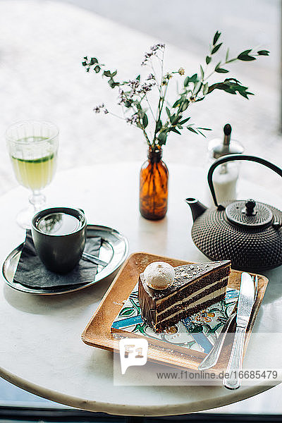 Stück Schokoladenkuchen  Teekanne  Tasse Tee auf dem Tisch in einem Café im Freien