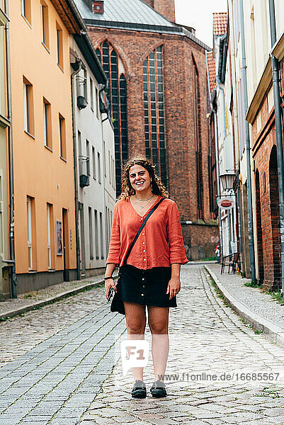 Fröhliche junge Frau auf der Straße in einer alten europäischen Stadt