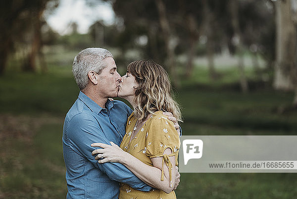 Portrait of married couple closely embracing and kissing outside