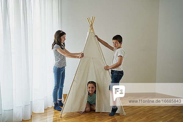 Kinder bauen ein Tipi-Zelt in ihrem Haus auf. Konzept der Kindheit