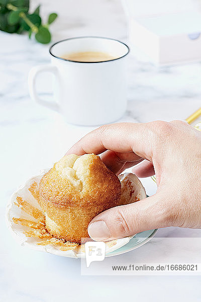 Die Hand einer Frau greift nach einem selbstgebackenen Muffin.