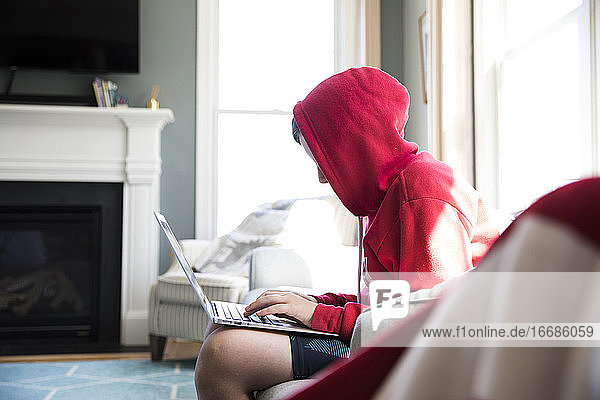 Seitenansicht von Tween Boy in Hooded Sweatshirt arbeiten auf Laptop-Computer
