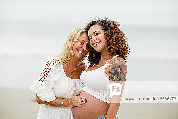 Mom Posing with Pregnant Daughter on Beach