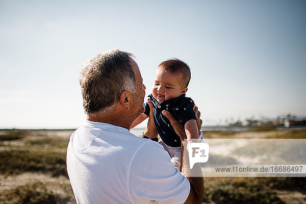Grandfather Holding Grandson While Standing on Beach