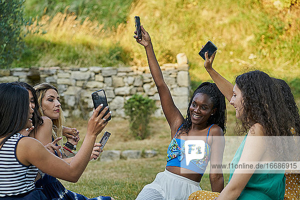 Group of women friends in a park looking at their smartphone