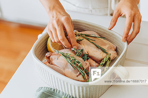 Hände  die rohe Wachteln oder Hühner mit aromatischen Kräutern zum Braten vorbereiten