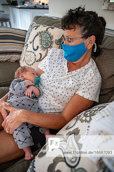 Woman wearing face mask holding her grandson.
