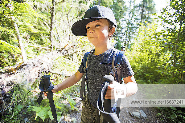 Young boy hiking with trekking poles  carrying backpack.