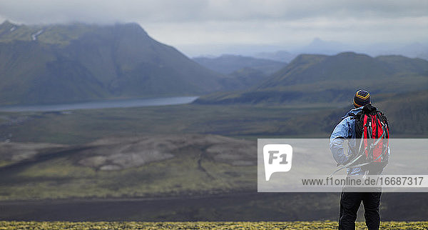 Mann mit Rucksack mit Blick auf das isländische Hochland