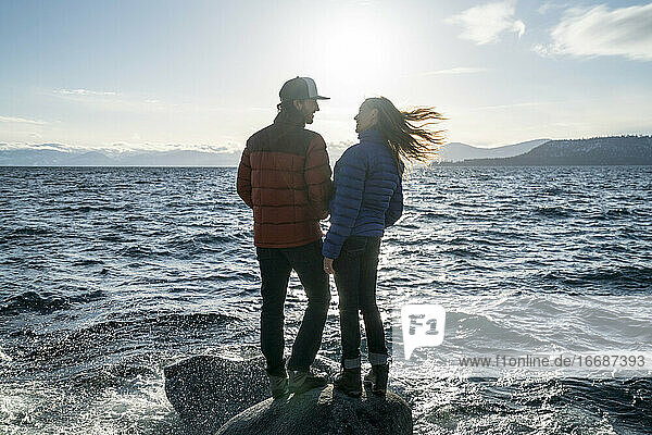 Junges verliebtes Paar steht auf einem Felsen im Lake Tahoe im Winter