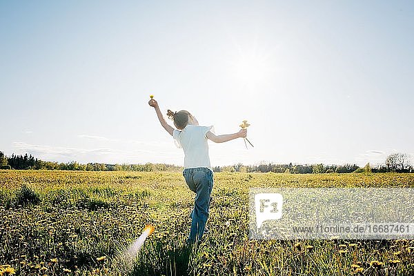 junges Mädchen tanzt durch ein gelbes Blumenfeld im Sommer