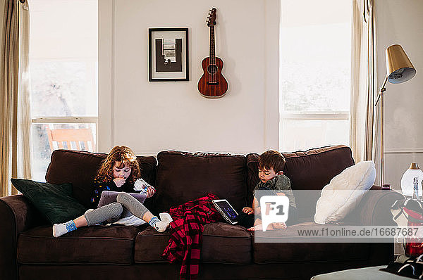 Young sister and brother using tablets while sick with flu