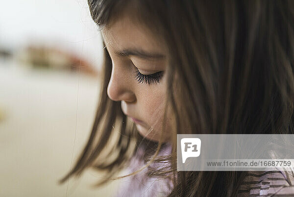 Headshot eines ernsten 6-jährigen Mädchens mit dunklem Haar und dichten Wimpern