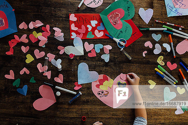 Draufsicht auf ein Mädchen  das Valentinsbasteleien und -karten herstellt