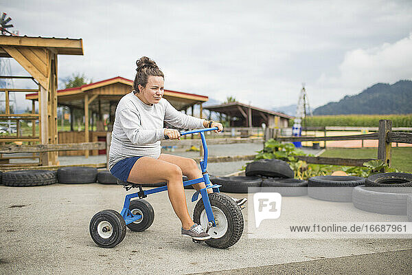 Fun expectant mother riding oversized tricycle on race track.