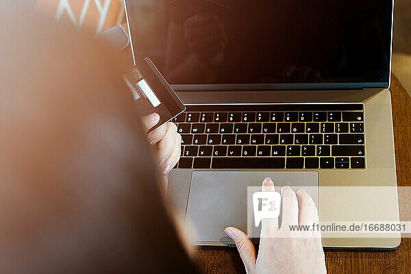 Eine Frau hält eine Kreditkarte in den Händen und benutzt einen Laptop. Online-Einkaufen