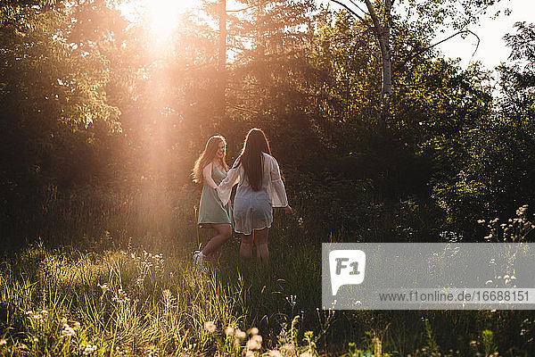 Zwei glückliche Freundinnen spazieren im Wald im Sommer