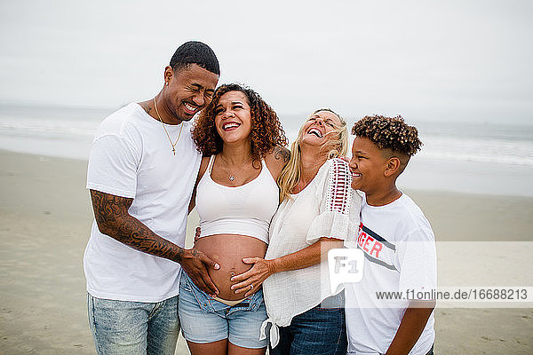 Family Posing & Laughing for Maternity Photos on Beach
