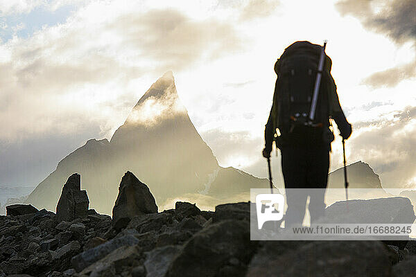 Backpacker approaches dramatic mountain summit  Canada.