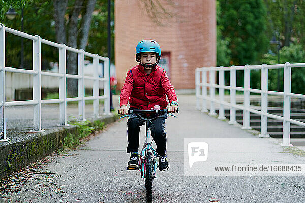 Junge auf einem Fahrrad mit blauem Helm und rotem Mantel