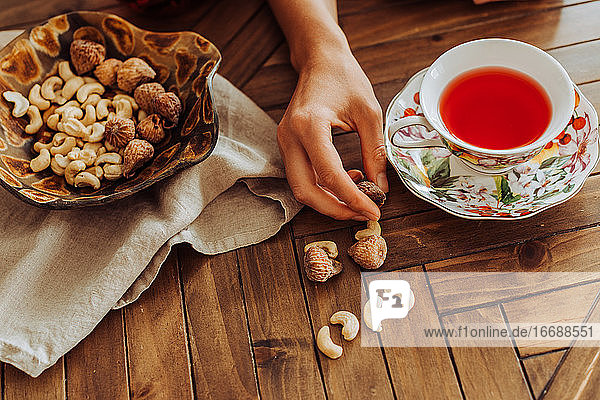 Tasse mit Hibiskustee  Hand und Trockenfrüchten auf einem Tisch