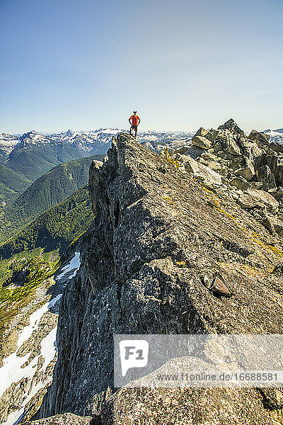 Trailrunner steht auf einem Berggipfel  am Rande einer Klippe.