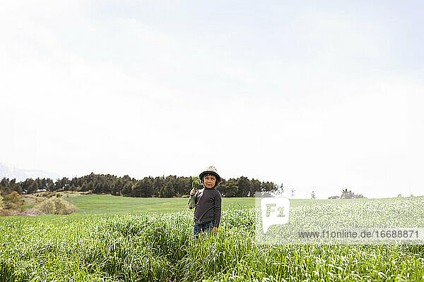 boy with a hat walking on meadow