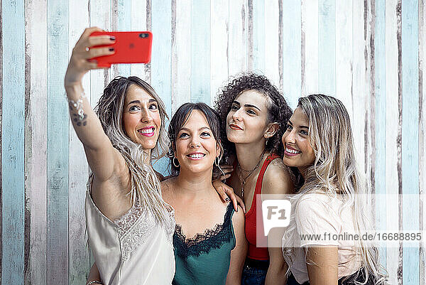 Freundinnen machen ein Selfie vor einer Holzwand