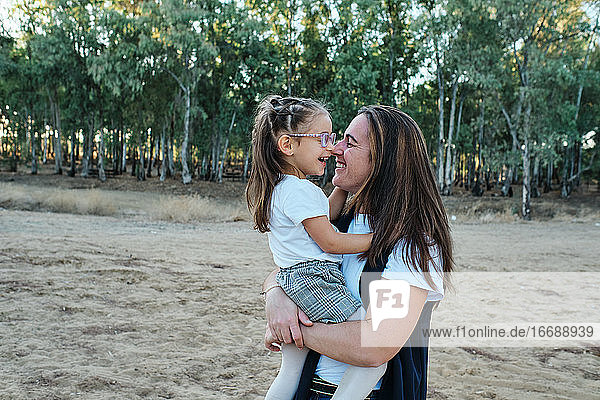 Die Mutter nimmt ihre Tochter in den Arm und spielt mit ihr  sie lächeln beide.