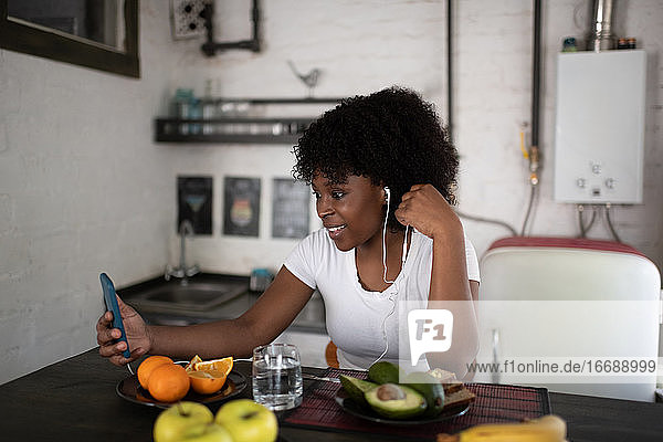 Afroamerikanische Frau führt während des Frühstücks einen Videoanruf durch