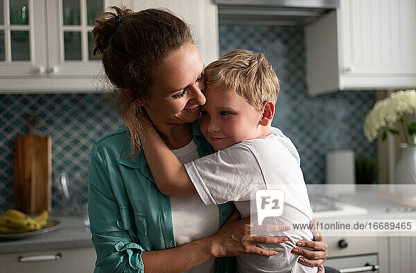 Glückliche Mutter  die ihren Sohn in der Küche umarmt