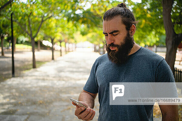 Mann im Park überprüft seine Trainingsergebnisse auf seinem Smartphone