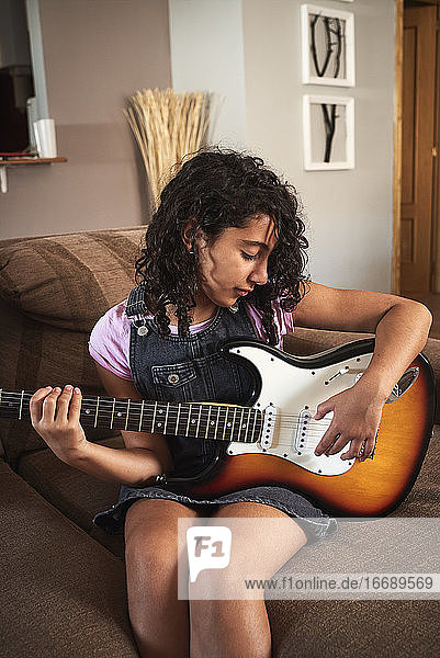 Ein kleines Mädchen spielt zu Hause auf der E-Gitarre
