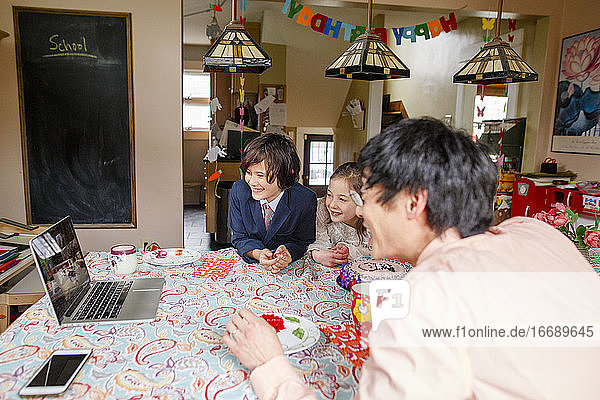 A happy family gather in front of computer for a zoom birthday party