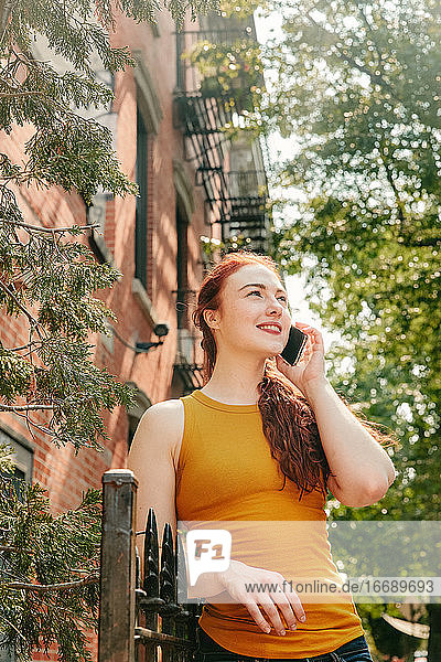 Junge Frau telefoniert fröhlich im Freien auf der Straße in Brooklyn.