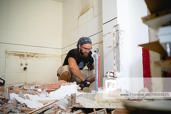 Ein Mann arbeitet an einem Heimwerkerprojekt  umgeben von Trümmern einer Mauer