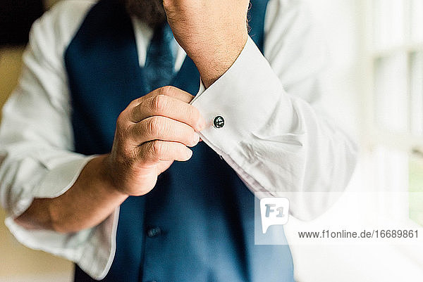 Portrait of a man in suit getting ready  fixing his cufflink