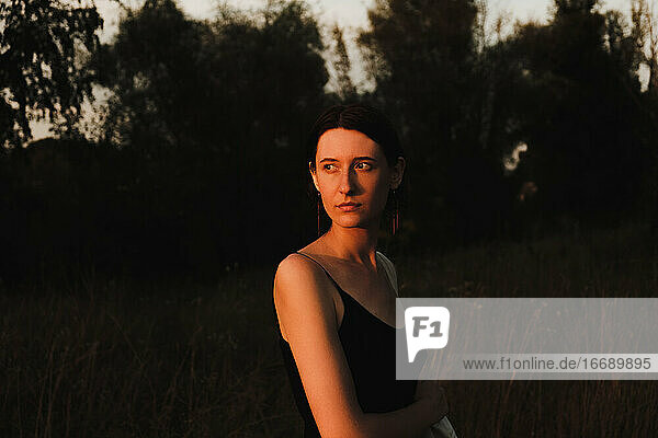 Junge erwachsene Frau im Kleid posiert bei Sonnenuntergang. Low key portrait of