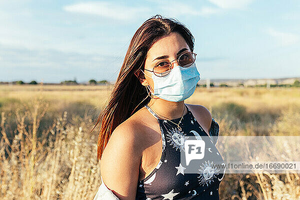 Serious teenager with a medical mask and sunglasses in the countryside