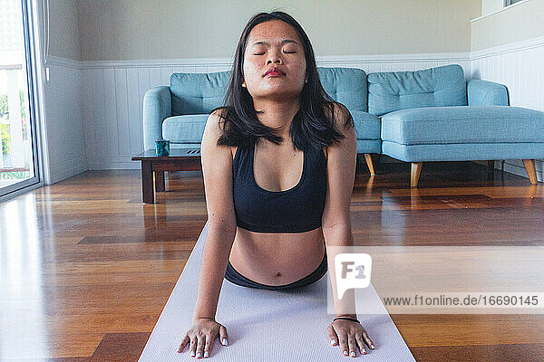 young woman doing yoga on yoga mat at home
