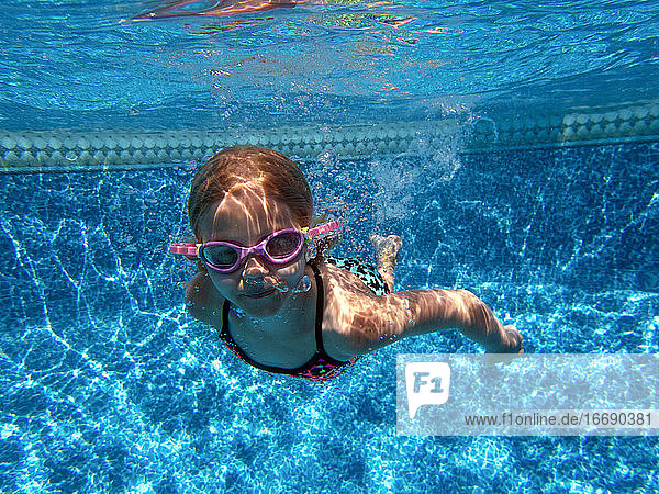 Girl swimming underwater with goggles on