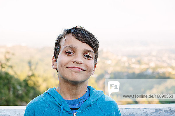 Ein lächelnder zehnjähriger Junge sonnt sich vor einem Aussichtspunkt in LA